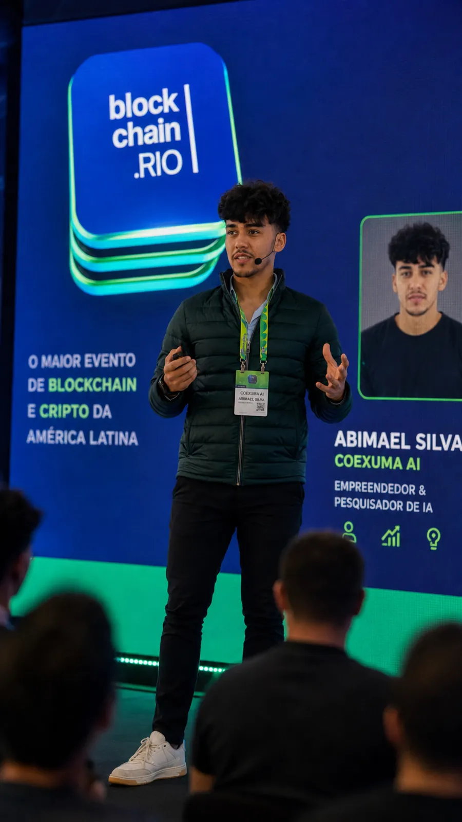 Abimael Silva palestrando no Blockchain.RIO, com o telão apresentando o empreendedor e pesquisador de IA